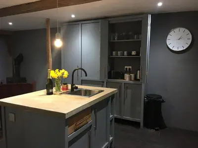 a kitchen with a sink and a clock on the wall at Square House Bildeston High street in Ipswich