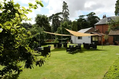 a patio with tables and chairs in a yard at Satis House Hotel in Yoxford