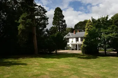 a white house with trees in the yard at Satis House Hotel in Yoxford