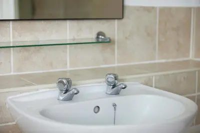 a bathroom sink with two faucets and a mirror at Old Ferry Boat by Greene King Inns in St Ives