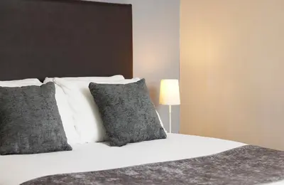 a bedroom with a bed with pillows and a lamp at Old Ferry Boat by Greene King Inns in St Ives