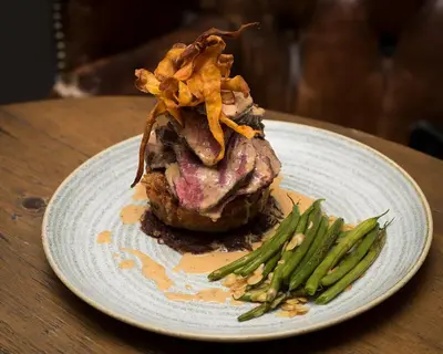 a plate of food with a piece of meat and green beans at The Bull Inn in Mildenhall