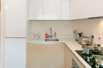 a kitchen with white cabinets and a sink at Modern & Exquisite Trumpington Townhouse with Parking & 5 mins to Papworth hospital in Cambridge