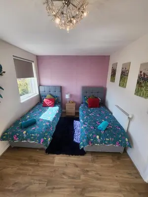 a bedroom with two beds and a chandelier at Modern & Exquisite Trumpington Townhouse with Parking & 5 mins to Papworth hospital in Cambridge