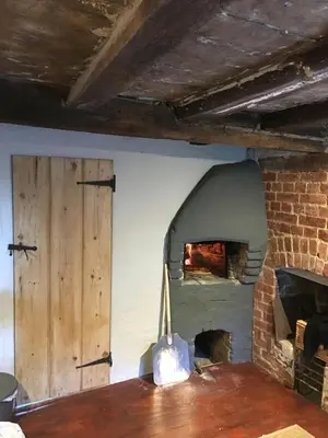 a pizza oven in a room with a brick wall at Watt Cottage in Ipswich