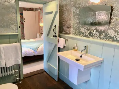 a bathroom with a sink and a bedroom with a bed at Crown House Great Glemham in Saxmundham