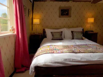 a bedroom with a large bed with red curtains at Crown House Great Glemham in Saxmundham