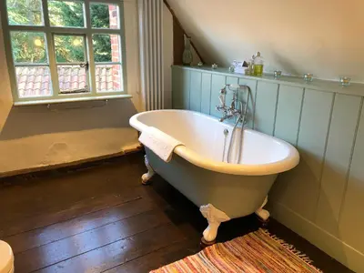 a bath tub in a bathroom with a window at Crown House Great Glemham in Saxmundham