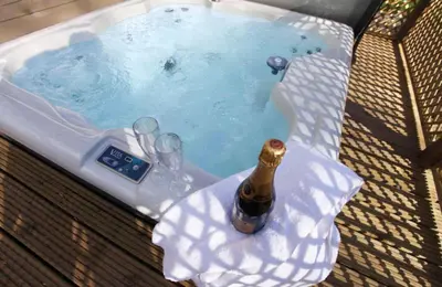 a hot tub with a bottle of champagne and wine glasses at Ransom Lodge in Chappel