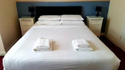 a large white bed with two white towels on it at The Langtry Hotel in Clacton-on-Sea