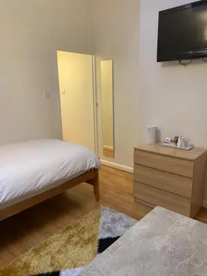a bedroom with a bed and a flat screen tv at Parkview Guesthouse in Cambridge
