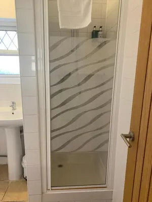 a shower with a glass door in a bathroom at Parkview Guesthouse in Cambridge