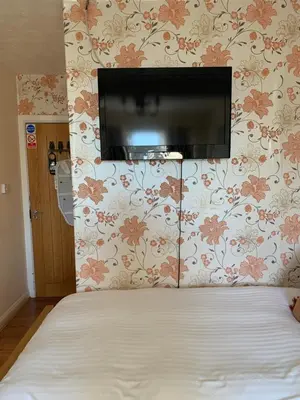 a bedroom with a bed with a tv on the wall at Parkview Guesthouse in Cambridge