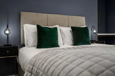 a bedroom with a large bed with green pillows at The Regent Aparthotel in Cambridge