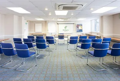 a classroom with blue chairs and a board in a room at Holiday Inn Ipswich by IHG in Ipswich