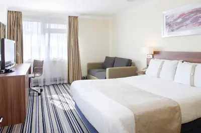 a hotel room with a large bed and a chair at Holiday Inn Ipswich by IHG in Ipswich