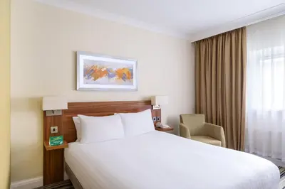 a hotel room with a bed and a chair at Holiday Inn Ipswich by IHG in Ipswich