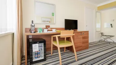 a room with a desk with a chair and a television at Holiday Inn Ipswich by IHG in Ipswich