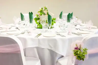 a white table with white plates and silverware at Holiday Inn Colchester by IHG in Colchester