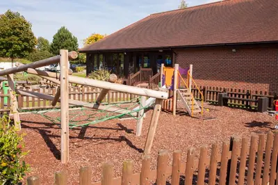 a playground in front of a building with a wooden fence at Holiday Inn Colchester by IHG in Colchester