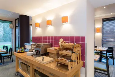 a kitchen with a counter with a table and chairs at Holiday Inn Cambridge by IHG in Cambridge