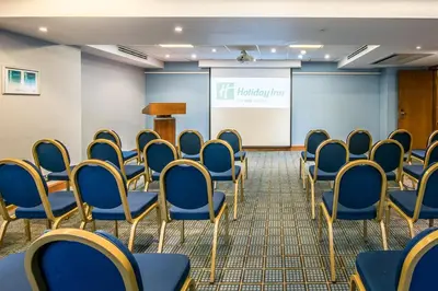 a conference room with blue chairs and a screen at Holiday Inn Cambridge by IHG in Cambridge