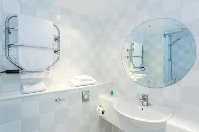 a white bathroom with a sink and a mirror at Holiday Inn Cambridge by IHG in Cambridge