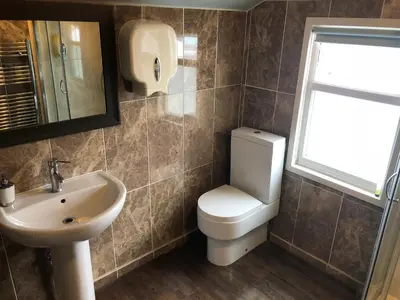 a bathroom with a toilet and a sink and a window at Ely Guest House in Ely
