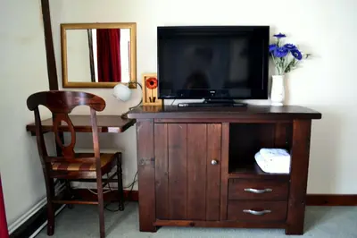 a wooden entertainment center with a tv and a chair at Ely Guest House in Ely