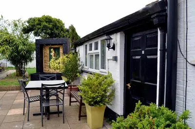 a patio with a table and chairs and a black door at Ely Guest House in Ely