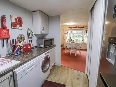 a kitchen with a washer and dryer and a dining room at The Lodge in Attleborough