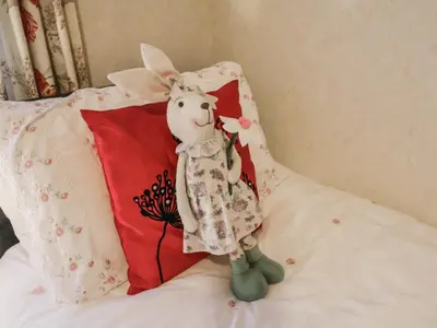 a stuffed rabbit sitting on a bed next to a pillow at The Lodge in Attleborough