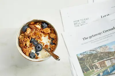 a bowl of granola next to a book at Tuddenham Mill Luxury Hotel in Tuddenham