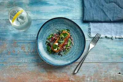 a plate of food on a wooden table with a fork at Tuddenham Mill Luxury Hotel in Tuddenham