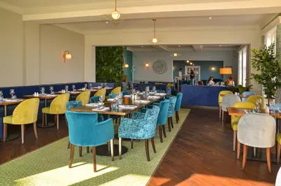 a restaurant with blue and yellow chairs and tables at Kingscliff, Holland on Sea in Clacton-on-Sea