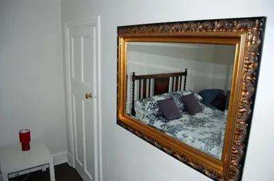 a mirror on a wall with a bed in it at The Castle Bar ROOM ONLY in Cambridge