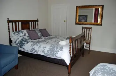 a bed in a room with a mirror and a blue chair at The Castle Bar ROOM ONLY in Cambridge