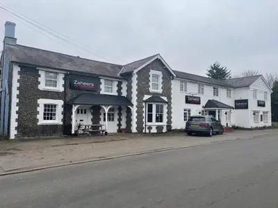 a building with a car parked in front of it at Zaheer's Hotel in Baldock