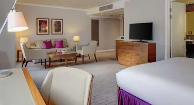 a hotel room with a bed and a living room at Hilton Cambridge City Centre in Cambridge
