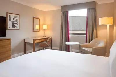 a hotel room with a bed and a desk and a window at Hilton Cambridge City Centre in Cambridge