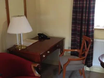 a room with a desk with a lamp and a chair at The Olde Windmill Inn in Great Cressingham