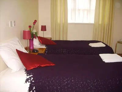 a bedroom with two beds with red pillows at Stansted Airport Lodge in Takeley
