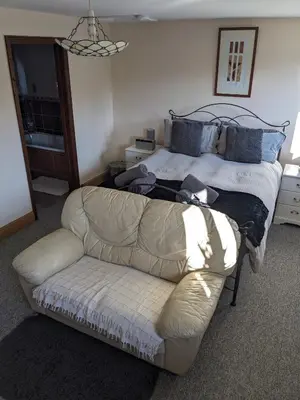 a living room with a couch and a bed at South Barn in Stanningfield
