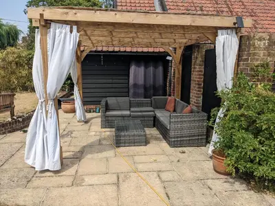 a pergola with a couch on a patio at South Barn in Stanningfield