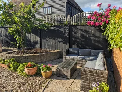 a patio with a couch and some flowers at South Barn in Stanningfield