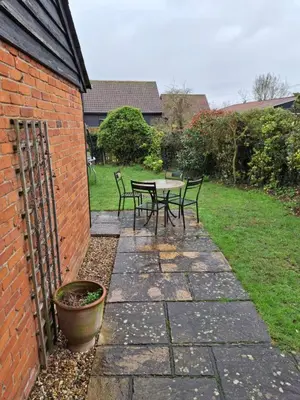 a patio with a table and chairs in a yard at South Barn in Stanningfield