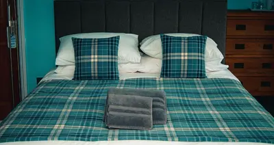 a green and white bed with pillows and a blanket at The Kings Head in New Buckenham