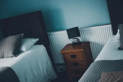 a bedroom with two beds and a lamp on a night stand at The Kings Head in New Buckenham