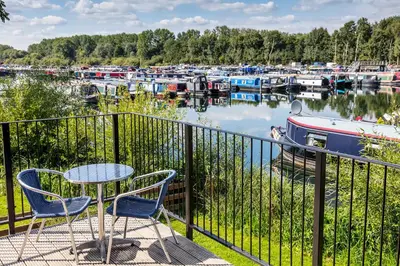 a table and chairs on a balcony with a marina at Roydon Marina Village Hotel in Roydon