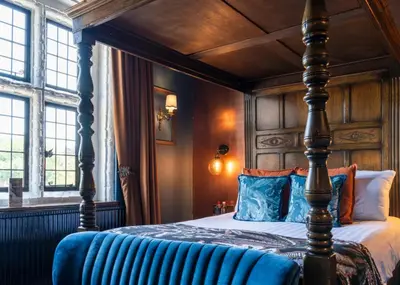 a bedroom with a canopy bed with blue pillows at Seckford Hall Hotel & Spa in Woodbridge